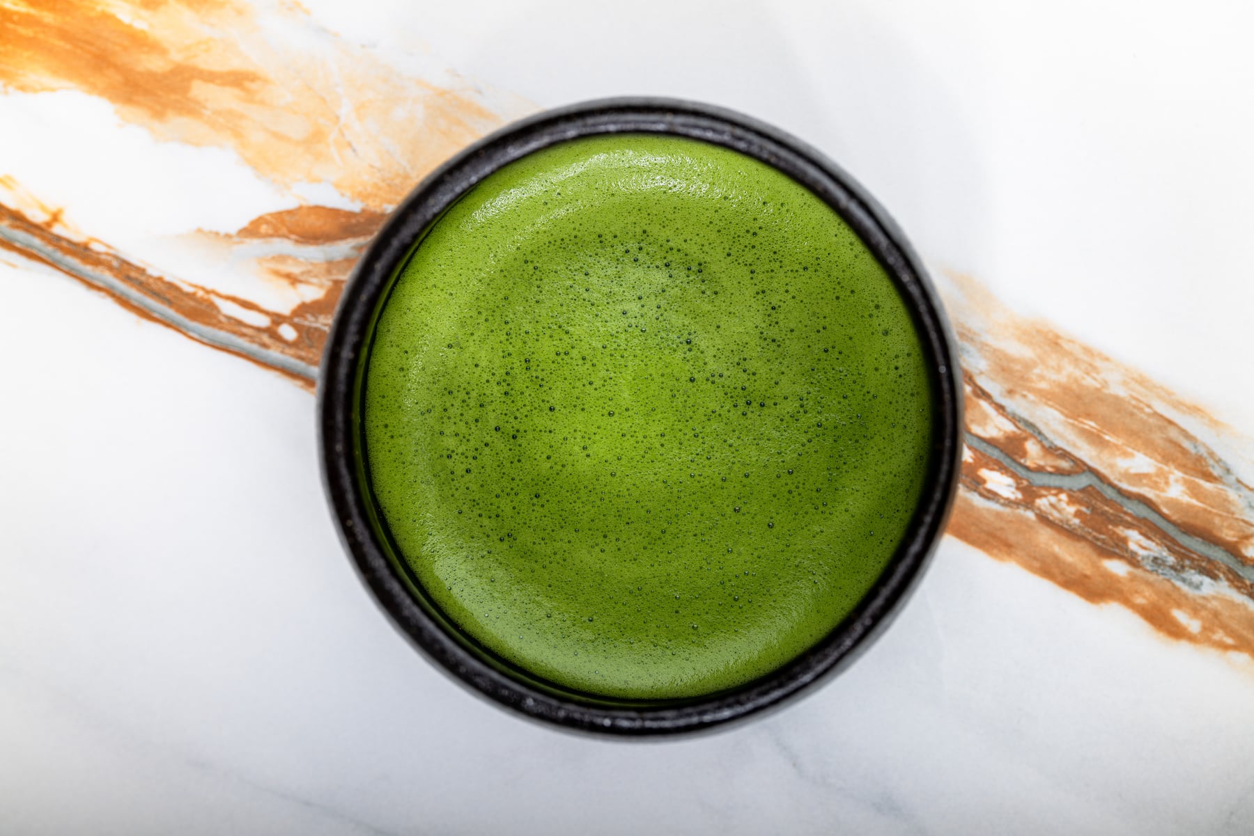 Aufgeschäumter Matcha in einer dunklen Schale