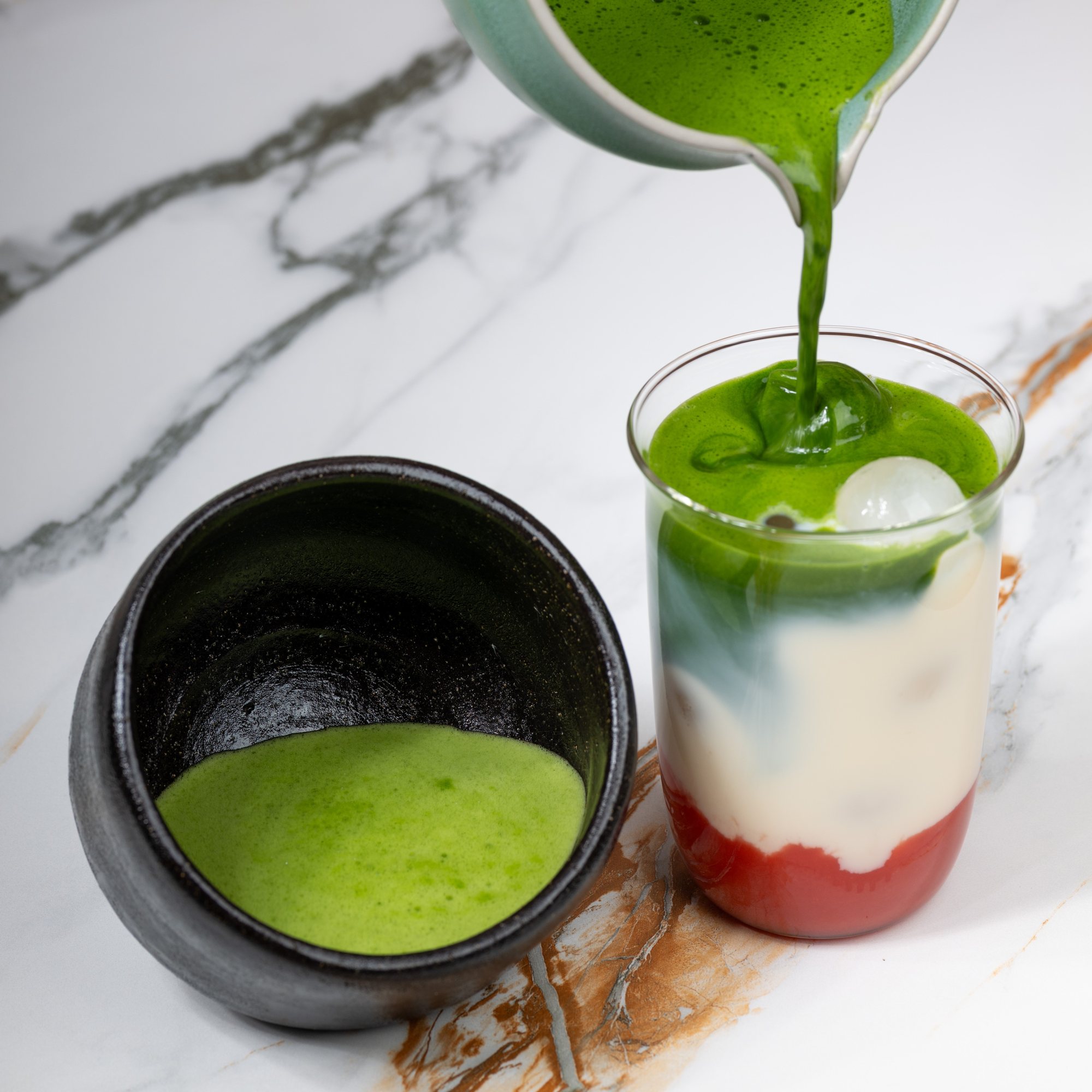 Matcha wird in einen geschichteten Iced Latte gegossen